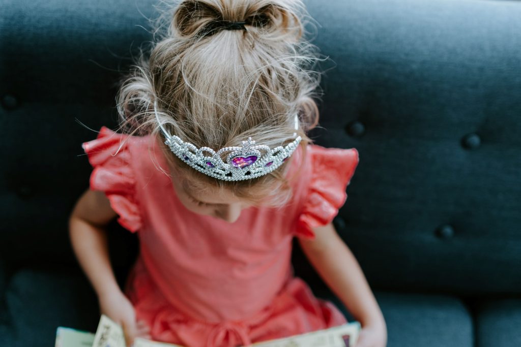 Mädchen mit Prinzessinnenkrone liest in einem Buch