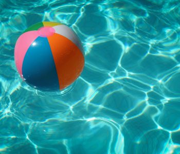 Das Foto zeigt einen Wasserball, der im Freibad auf dem Wasser schwimmt