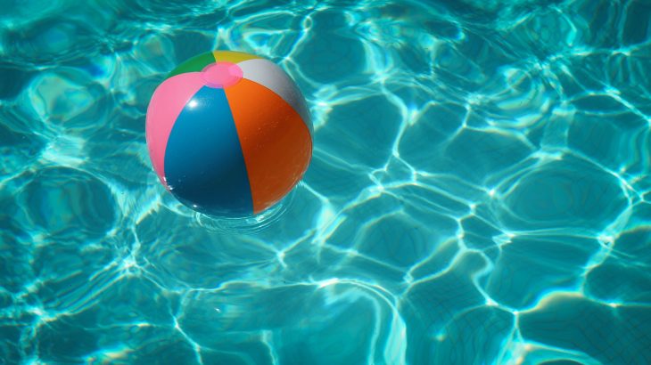 Das Foto zeigt einen Wasserball, der im Freibad auf dem Wasser schwimmt