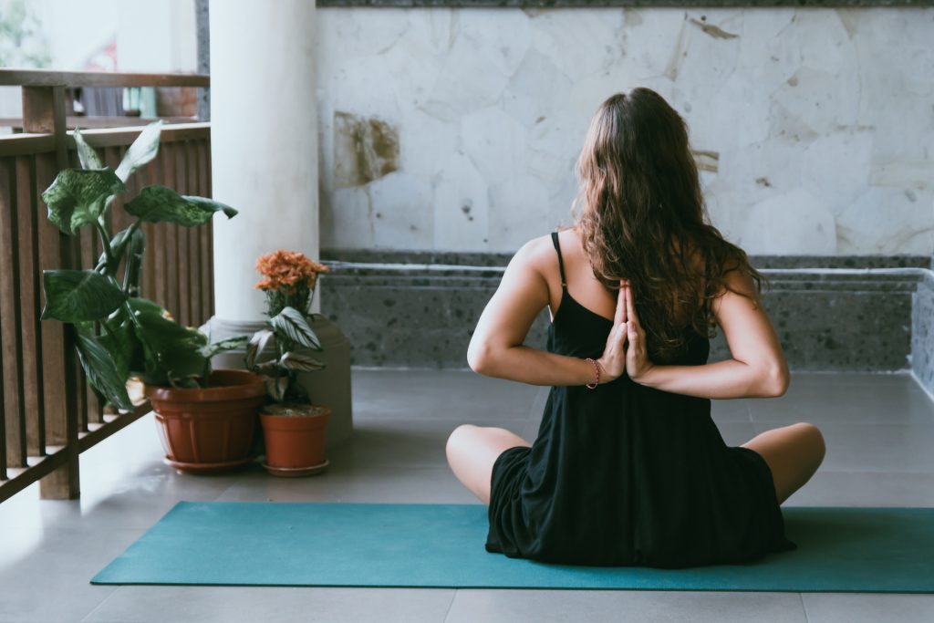 Frau zeigt eine hinduistische Begrüßung auf einer Yogamatte - zum Beistrag Geburtsvorbereitung