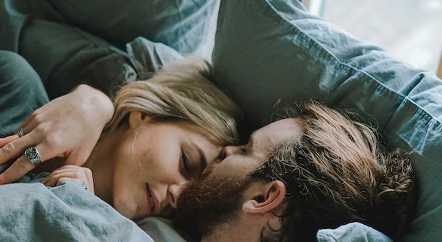 Paar kuschelt im Bett - Beitragsbild zum Thema sichere Verhütung in der Stillzeit
